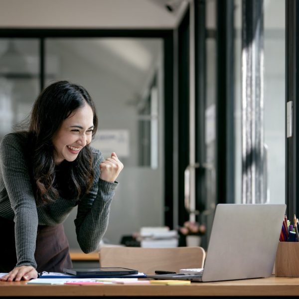 Beautiful Asian woman celebrate with laptop, successful business startup small business concept.